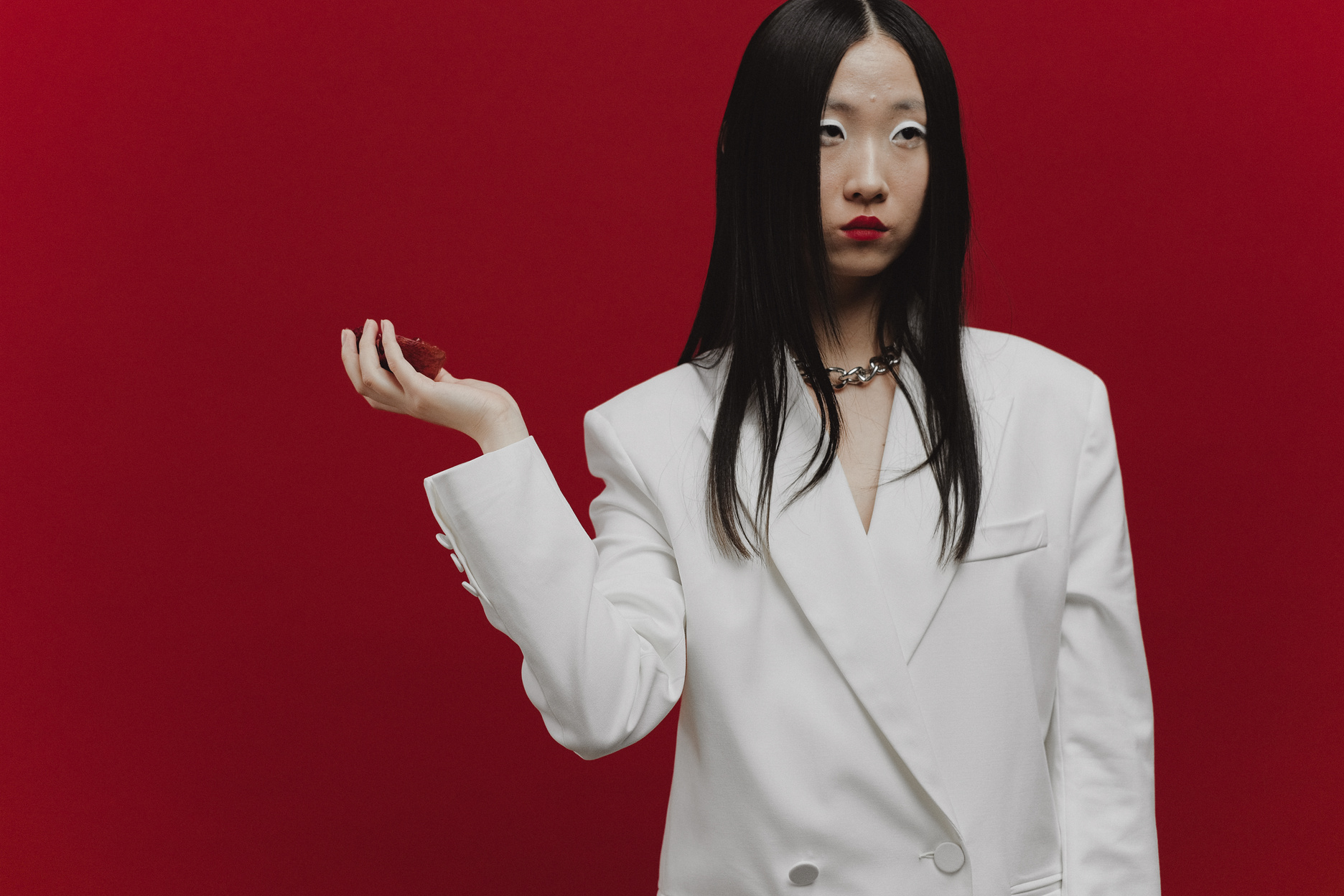 Woman in White Blazer Standing Against Red Background